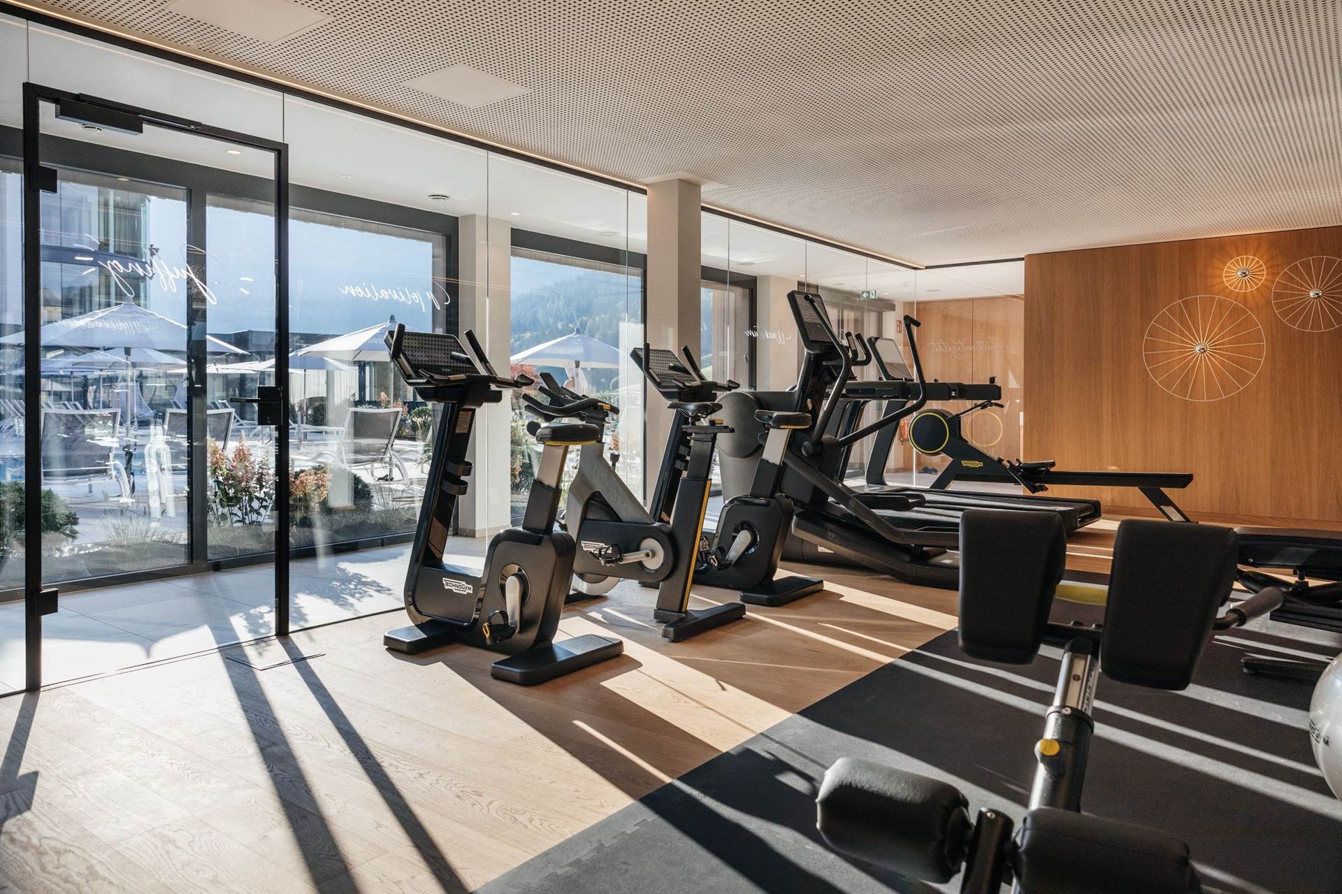 In unserem Fitnessstudio finden Sie das passende Angebot Cardio-Geräte im Fitnessraum mit Panoramafenstern mit Blick nach Draußen.