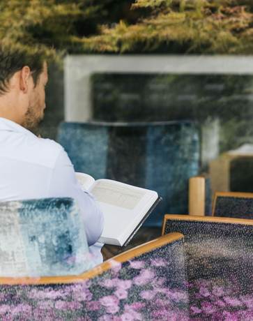 Ein Mann sitzt in einem Sessel und liest ein Buch.