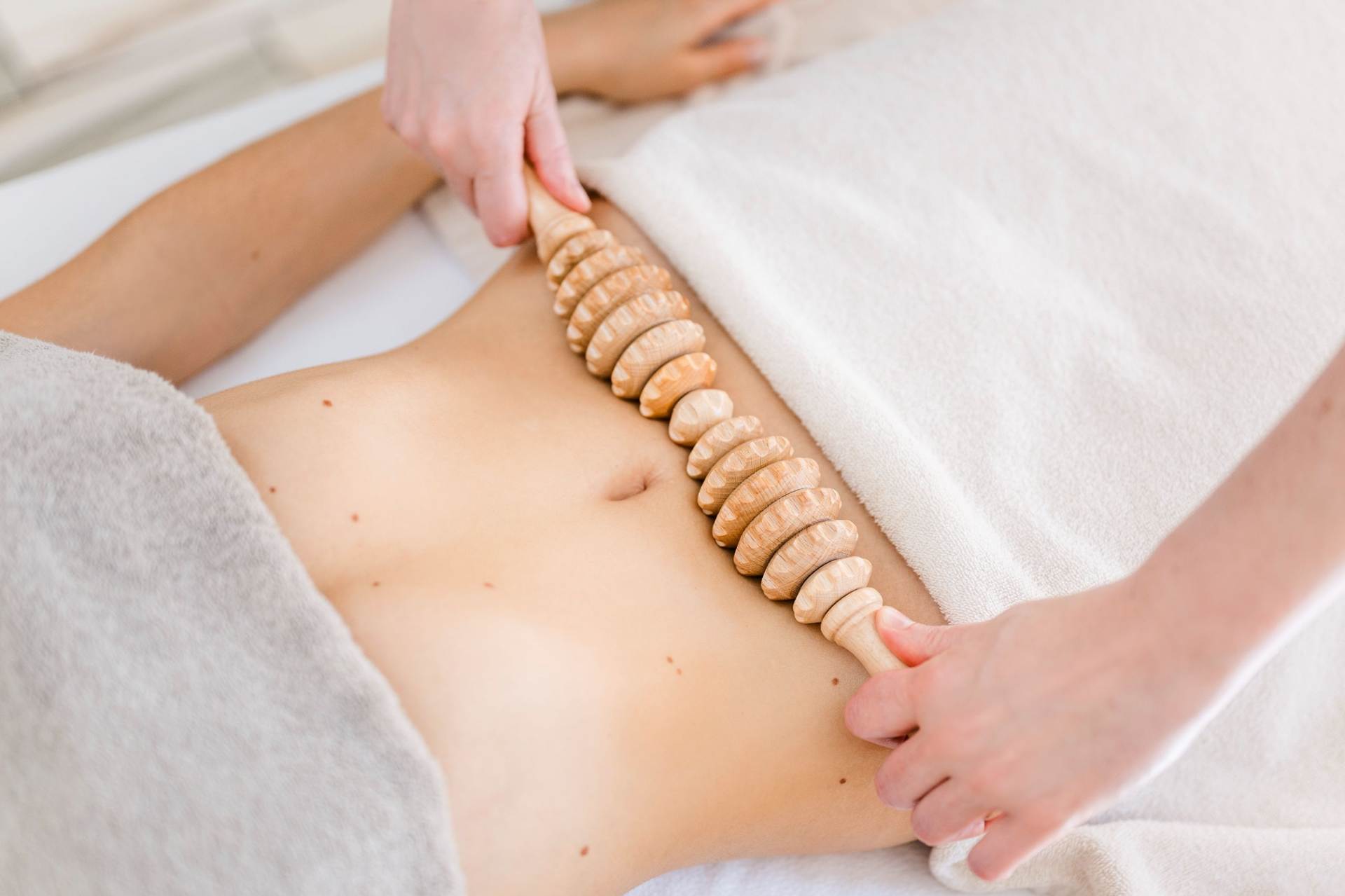 Probieren Sie eine Behandlung der klassischen Körper-Maderotherapie Eine Frau wird mit einem Holzroller massiert.