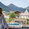 Eine Frau im Bademantel schaut vom Balkon aus auf den Außenpool des Hotel Juffing.